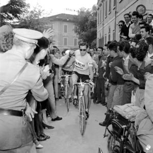black and white photo of Fausto Coppi flanked by the crowd in the city of Siena, during the Giro d'Italia. 1952