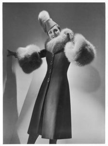 A gray three-quarter length coat with large buttons teamed with a brimless fez shaped hat by Jeanne Lanvin. Mary Evans Picture Library, Londra, Gran Bretagna