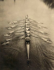 Rowing crew. Early 20th-century photograph of eight rowers and a coxswain rowing on a river. 1911 circa.