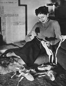 Black and white photo of the english dancer Margot Fonteyn in her house reparing her ballet shoes