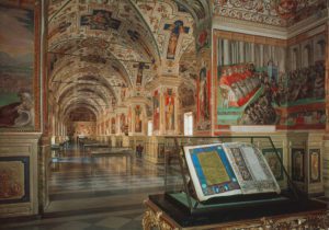 View of the frescoed and vaulted Vatican library. close up a manuscript in a protective case