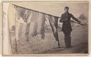 Sergeant Alex Rogers with the flag of the Eighty-third Pennsylvania Volunteers, Third Brigade, First Division, Fifth Corps, Army of the Potomac battalion. Photograph, ca.1863 - ME10793