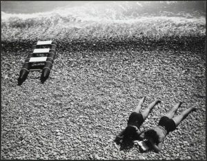 black and white photo of bathers on a pebble beach Nice