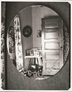reflection in an oval mirror of a room in a private home late 1940s,
