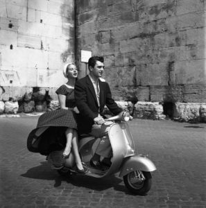 Actor Edmund Purdom and actress Genevieve Pageon a Vespa in the streets of Rome.