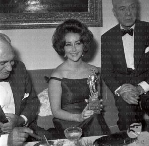 Elizabeth Taylor al cocktail in occasione del David di Donatello, tiene in mano la statuetta, accanto c'e il produttore Walter Wagner