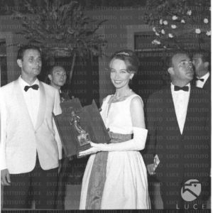Leslie Caron, smiling, shows the David di Donatello Award. Taormina. 1959 - L213789