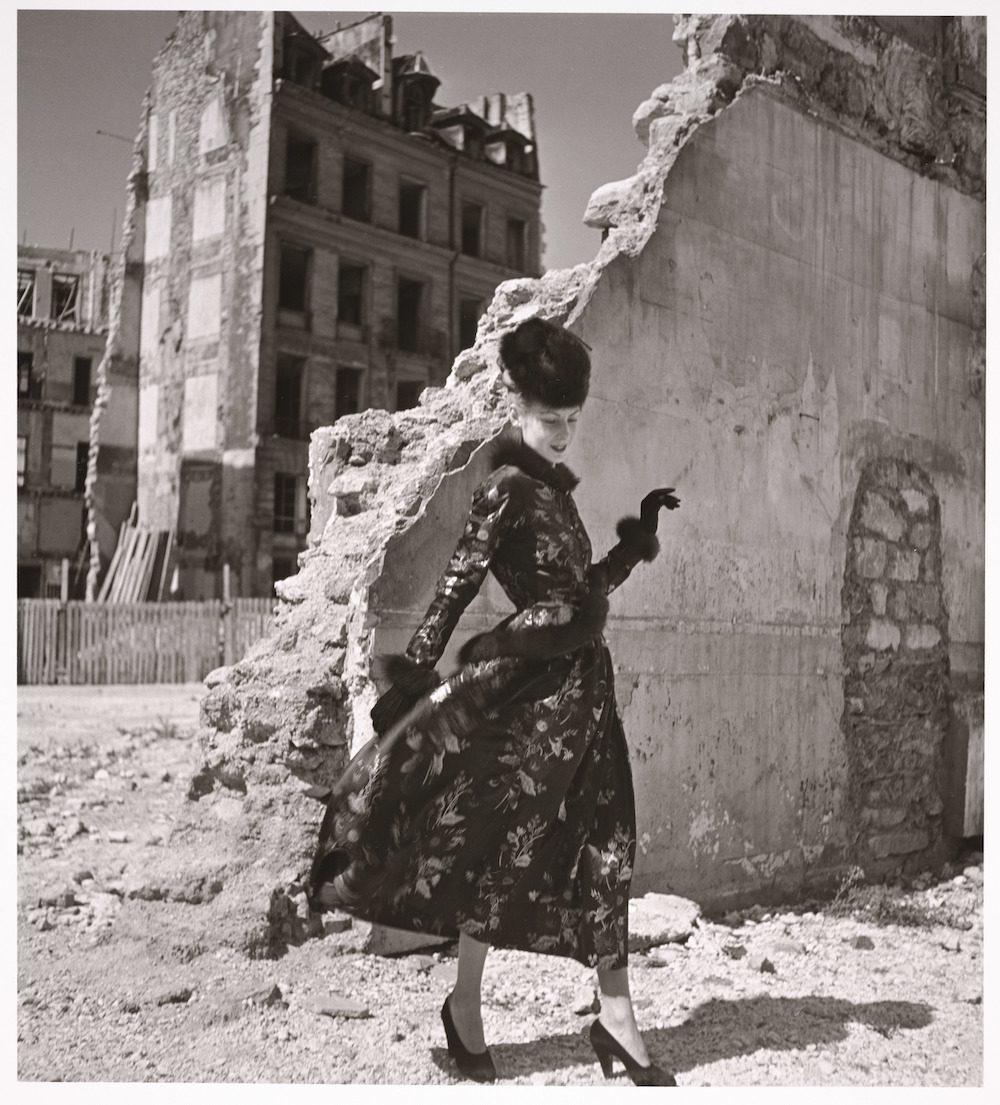 Woman in flowered dress standing by crumbled wall, Paris. fashion against war ruins